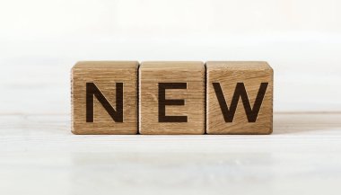 Three wooden cubes with word NEW, on white background.