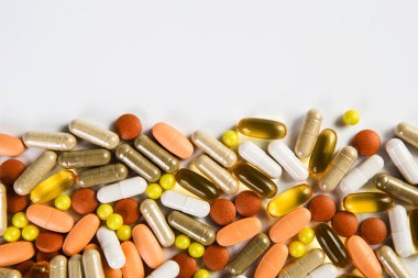 Heap of medicine colored pills, tablets and capsules on a white background.