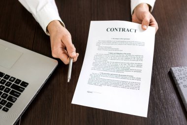 Businessman handing over a contract for signature offering a silver ballpoint pen in his hand. clipart