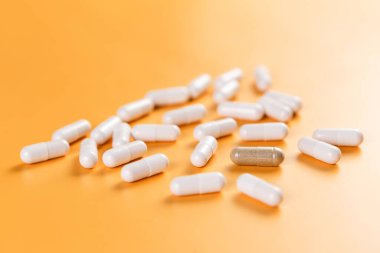 Opposition. A lot of white pills and one brown on a yellow background. The problem of choice and efficiency. Health and medicine. clipart