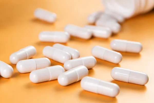 Eczacılık ilaçları beyaz haplar, tabletler veya sarı arka planda kapsüller..