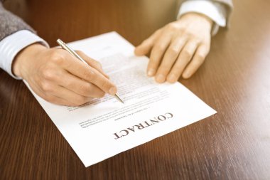 Ofisteki masada kontrat belgelerini okuyan bir adam. Sıcak güneş ışığı.