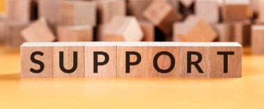 Bir çok bulanık kübün bulunduğu sarı bir zemin üzerinde tahta küplerden oluşan destekleyici sözcük..