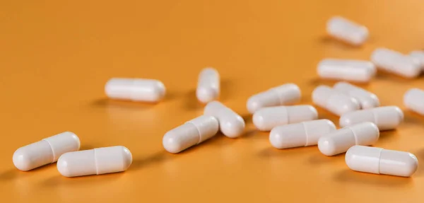 Eczacılık ilaçları beyaz haplar, tabletler veya sarı arka planda kapsüller..