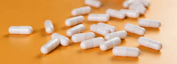 Eczacılık ilaçları beyaz haplar, tabletler veya sarı arka planda kapsüller..