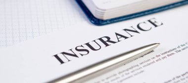 Gümüş tükenmez kalemle sigorta sözleşmesinin kapanışı ve arka planda planlama.