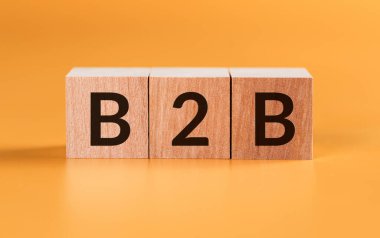 Sarı zemin üzerinde B2B harfleri olan tahta küpler. İş Konsepti resmi.