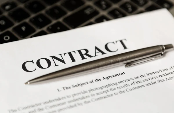 Sözleşmeyi imzalamak için tükenmez kalem. Kalem ve sözleşme laptopta..