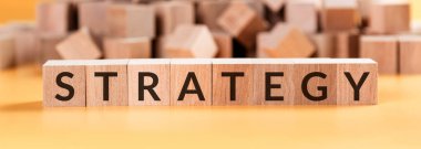Sarı arka planda tahta küplerle ilgili strateji kelimesi, iş konseptinde başarılı.