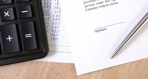 Sözleşme ya da anlaşma belgesinin bir parçası, gümüş tükenmez kalem ve hesap makinesiyle imza alanı.