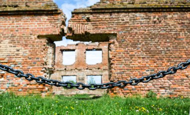 Black fence in front of the destroyed wall. The concept of conservation of attractions.