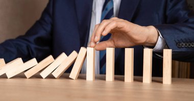 İş adamı eli Düşen Tahta Dominoların sürekli devrilmesinden ya da risk almasından, strateji ve iş için başarılı müdahale kavramının etkilerini durdurur.