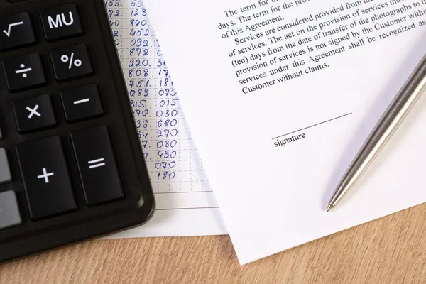 A part of contract or agreement document, space of signature with a silver pen and calculator.