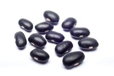 Beyaz arka planda dağınık ışık ve seçici odaklı siyah fasulyelerin yukarıdaki makro görüntüsü. Sağlıklı gıda ve doğal ürün kavramları için ideal.