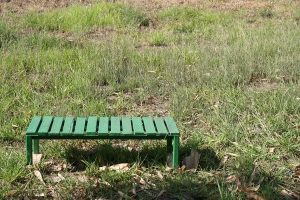 Зеленая скамейка на траве — стоковое фото