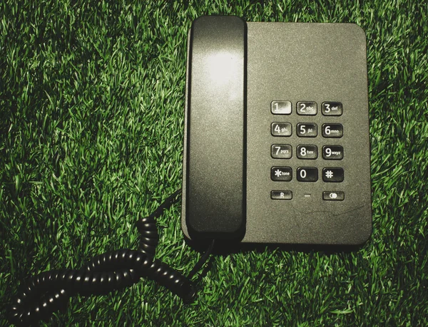 Black telephone on green grass — Stock Photo, Image