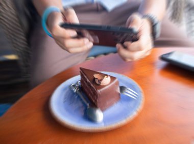 Kafe 'de otururken sosyal ağ fotoğrafı için cep telefonuyla tatlıları çekerken erkeklerin ellerini kapat.