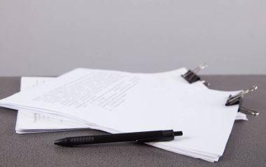 Ofis masasında ataçlı ve kalemli kağıt yığını. Yıllık rapor dosyaları için iş belgeleri. İş ofisleri kavramı.