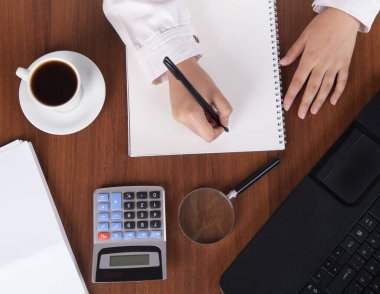 Ofiste bir fincan kahveyle çalışan genç bir iş kadını..