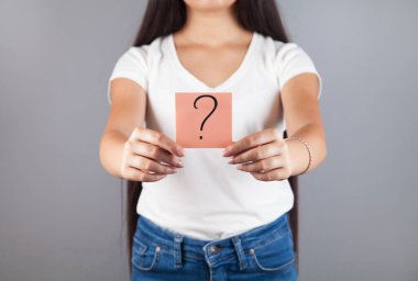 Elinde soru işareti tutan genç bir kadın..