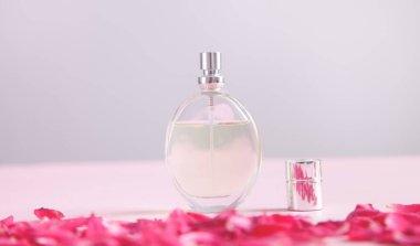 Güzel kadın parfümü, izole edilmiş pembenin arka planında. Güzel gül yapraklarına sarılmış.