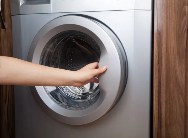 Woman using washing machine. Washing machine at home.