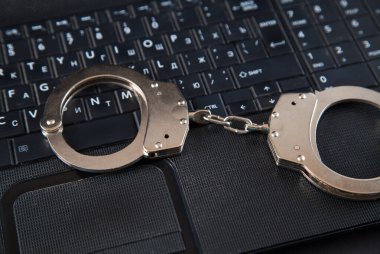 Polis metali kelepçeler ve bilgisayar klavyesi.