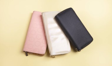 İzole edilmiş sarı arka planda kadın cüzdanları..