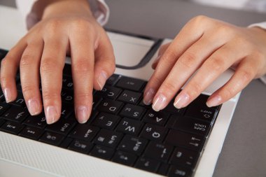 Beyaz bir bilgisayar klavyesinde kadın elleri.