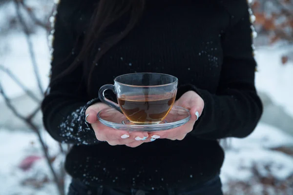Elinde çay tutan bir kadın. Açık havada. Kış günü.