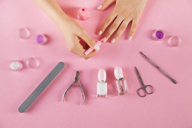 İzole edilmiş pembe arka planda manikür aksesuarları. Kadın elleri.