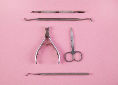 İzole edilmiş pembe arka planda manikür aksesuarları.