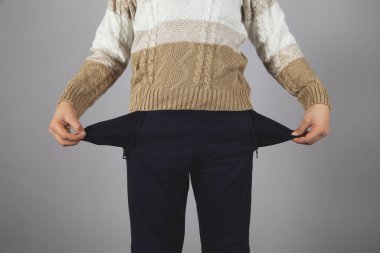 Çocuk onun boş ceplerini gösteriyor. Gri arkaplan. 