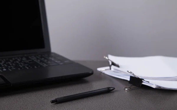 Stack of paper documents with pen and computer, on office desk. Business papers for annual report files. Business offices concept.