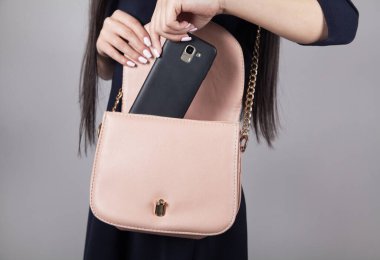 Kadın telefonu çantasına koyar..