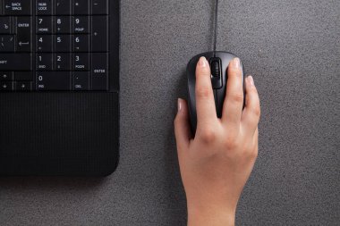 Masada bilgisayar faresi olan bir kadın eli. Siyah bilgisayar. 