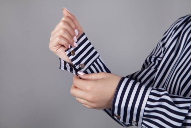 Genç bir kadın gömleğinin düğmelerini bağlıyor..