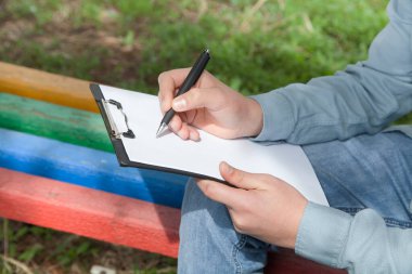 Kafkasyalı bir adam dokümanlara kalemle yazar. Açık havada..