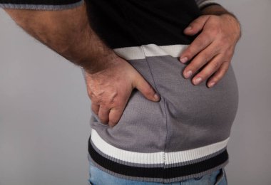 Sırt ağrısı çeken bir adam. Gri arkaplan. 