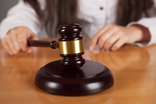 Судья женщина. Судья молоток. Деревянный стол.