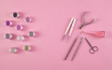 İzole edilmiş pembe arka planda manikür aksesuarları.