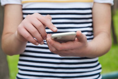 Elinde cep telefonu tutan beyaz bir adam var. Açık havada..