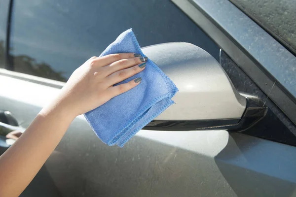 Woman washes the dirty car with a cloth.