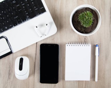 Akıllı telefon, kablosuz kulaklık, dizüstü bilgisayar ve ahşap arka planda aksesuarlar..