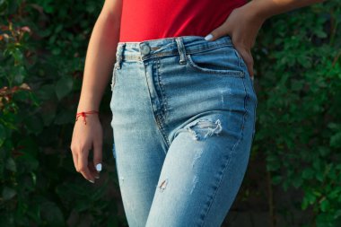 Mavi yırtık kotlu genç bir kızın bacakları.