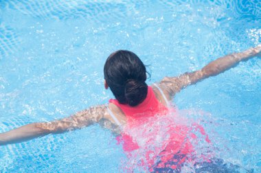 Kız havuzda banyo yapıyor. Güneşli bir gün.