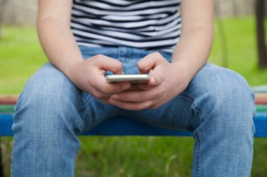 Elinde cep telefonu tutan beyaz bir adam var. Açık havada..