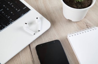 Akıllı telefon, kablosuz kulaklık, defter ve ahşap arka plandaki aksesuarlar..