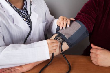 Doktor hastanın kan basıncını basınç cihazıyla ölçüyor..