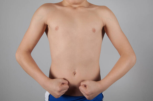 Strong boy with a fist. Gray background.